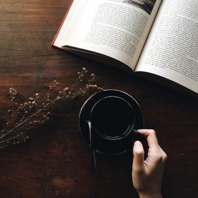 Featured image shows a wooden table with a open book, flowers, and a coffee cup.